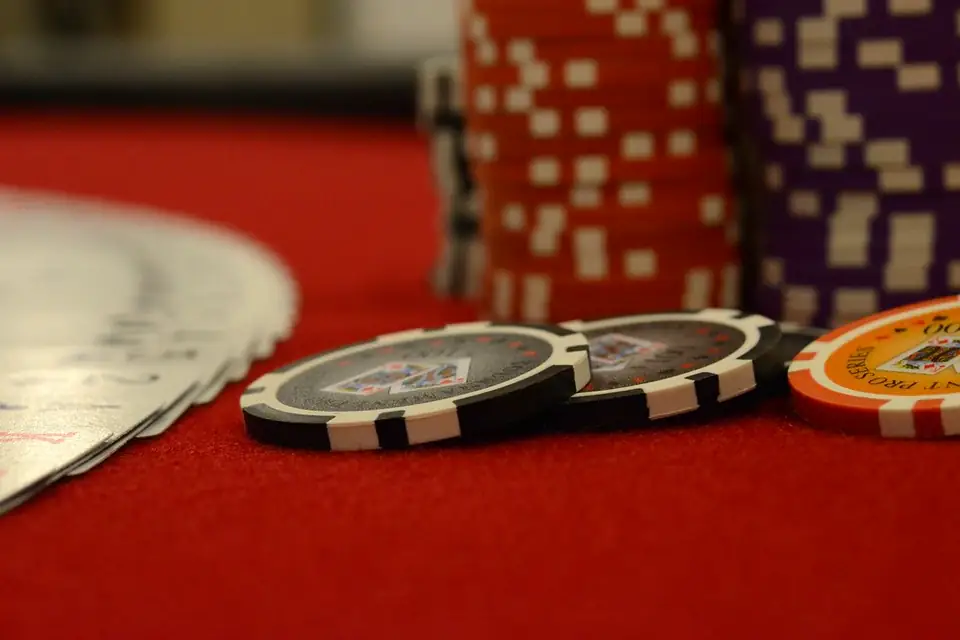 Casino chip stacks and playing cards on a red felt table