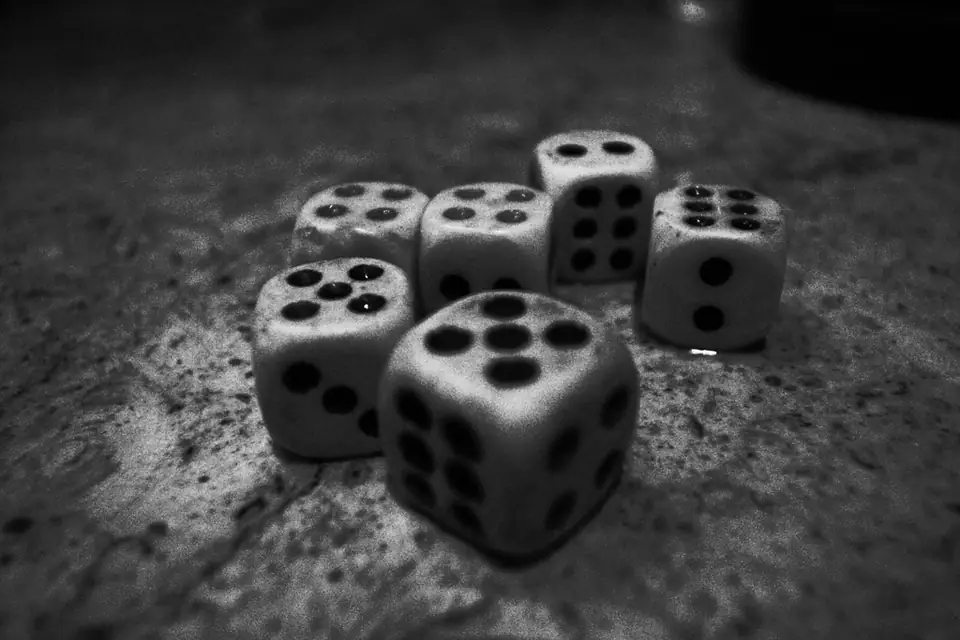 White dice scattered on a dark stone surface